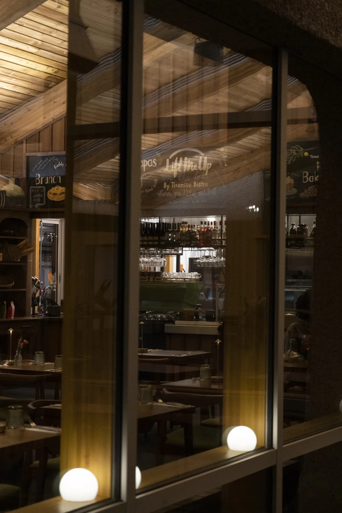 View through the window into the bar at night, candle-lit dining room beyond